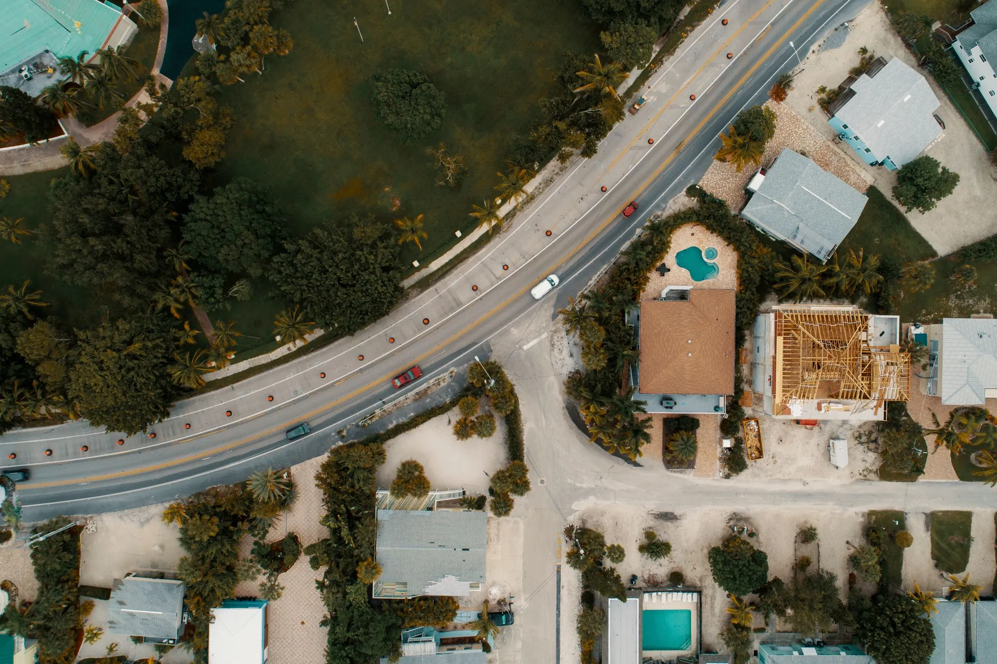 An aerial view of houses along a road among trees