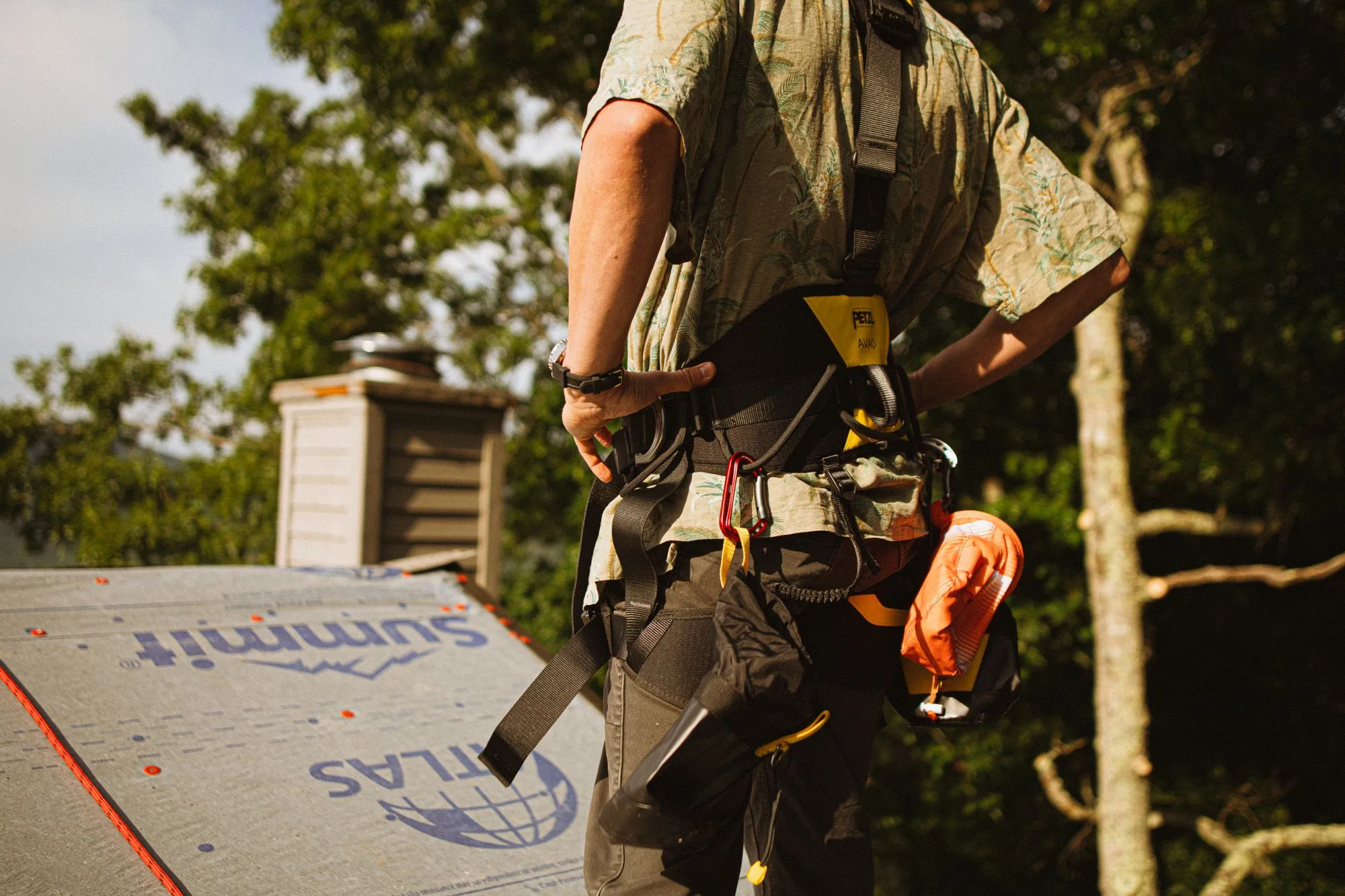 A roofer's safety harness clipped on above a sheeted roof slope