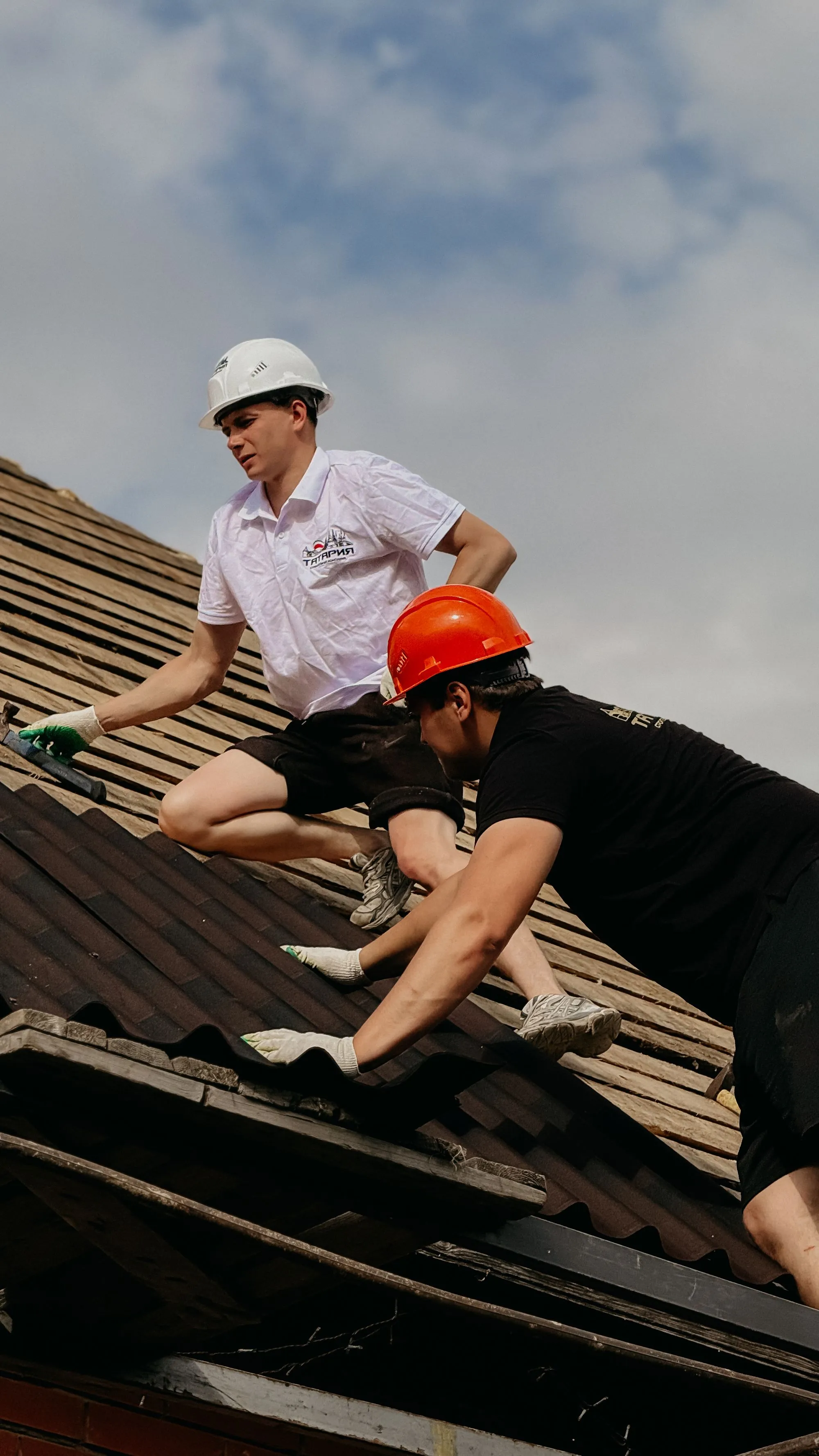 Two roofers in hard hats working a slope together